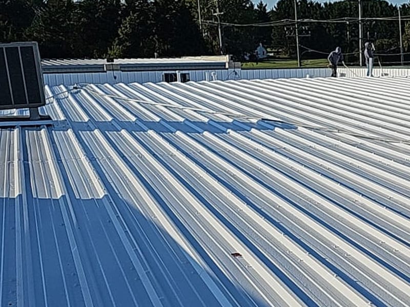 Image of a metal roof being restored with an AP-6100 Modified Liquid Rubber Roof Coating system being applied with rollers.