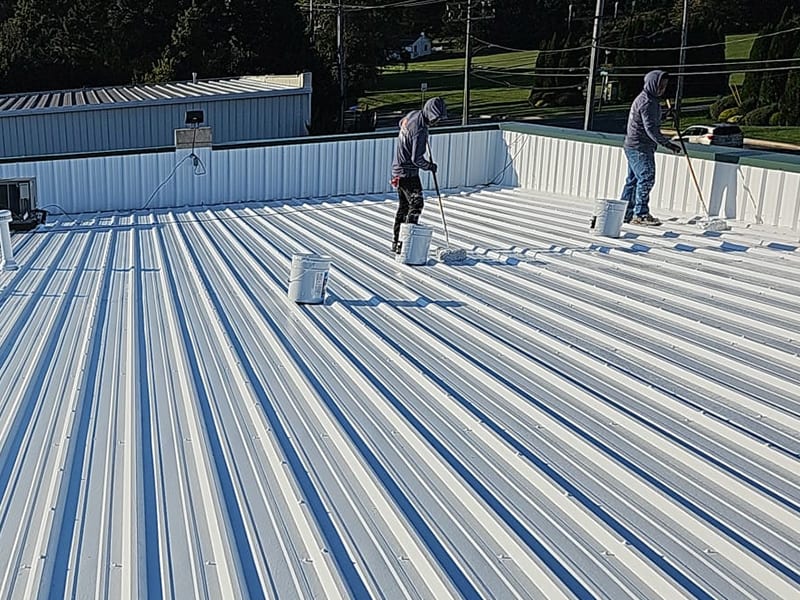 Image of roof restoration crew applying AP-6100 Modified Liquid Rubber Roof Coating with rollers.